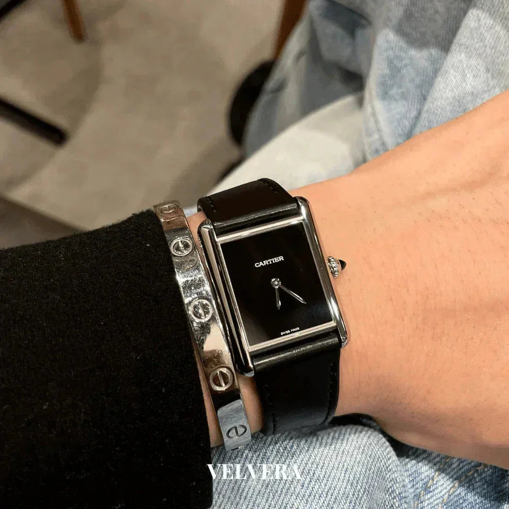 Cartier black rectangular watch with leather strap and silver bracelet on wrist