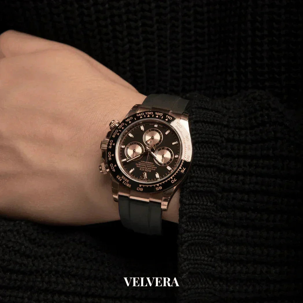 Luxury black and gold chronograph watch on wrist with black sweater, Velvera branding