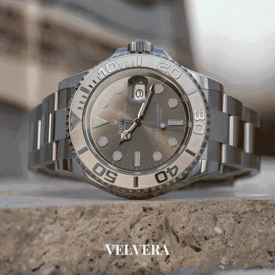 Luxury silver Rolex watch with metal band on a stone surface, VELVERA branding below