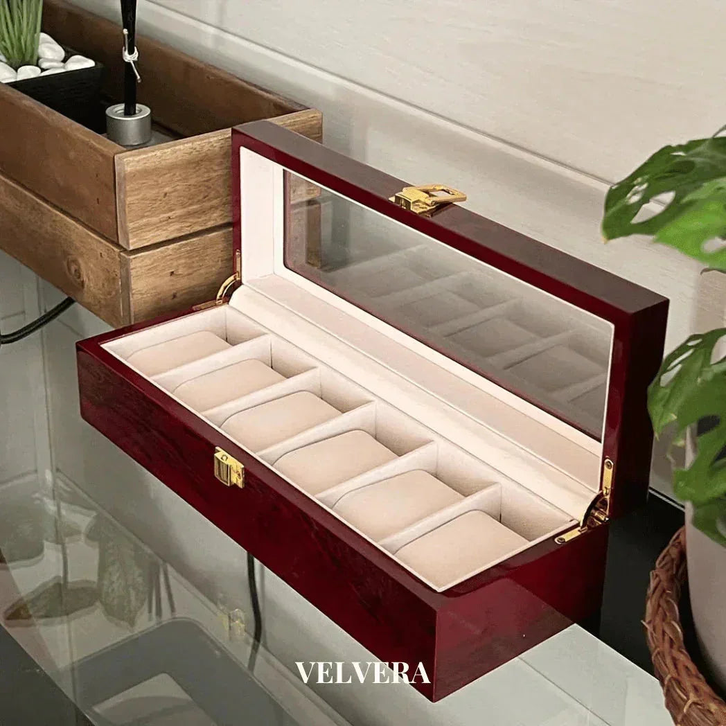 Velvera wooden watch box with glass lid and beige interior on a glass table