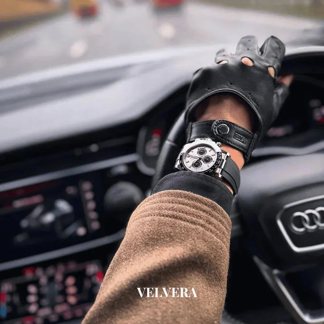 Man wearing black racing gloves and luxury watch driving Audi, Velvera branding visible
