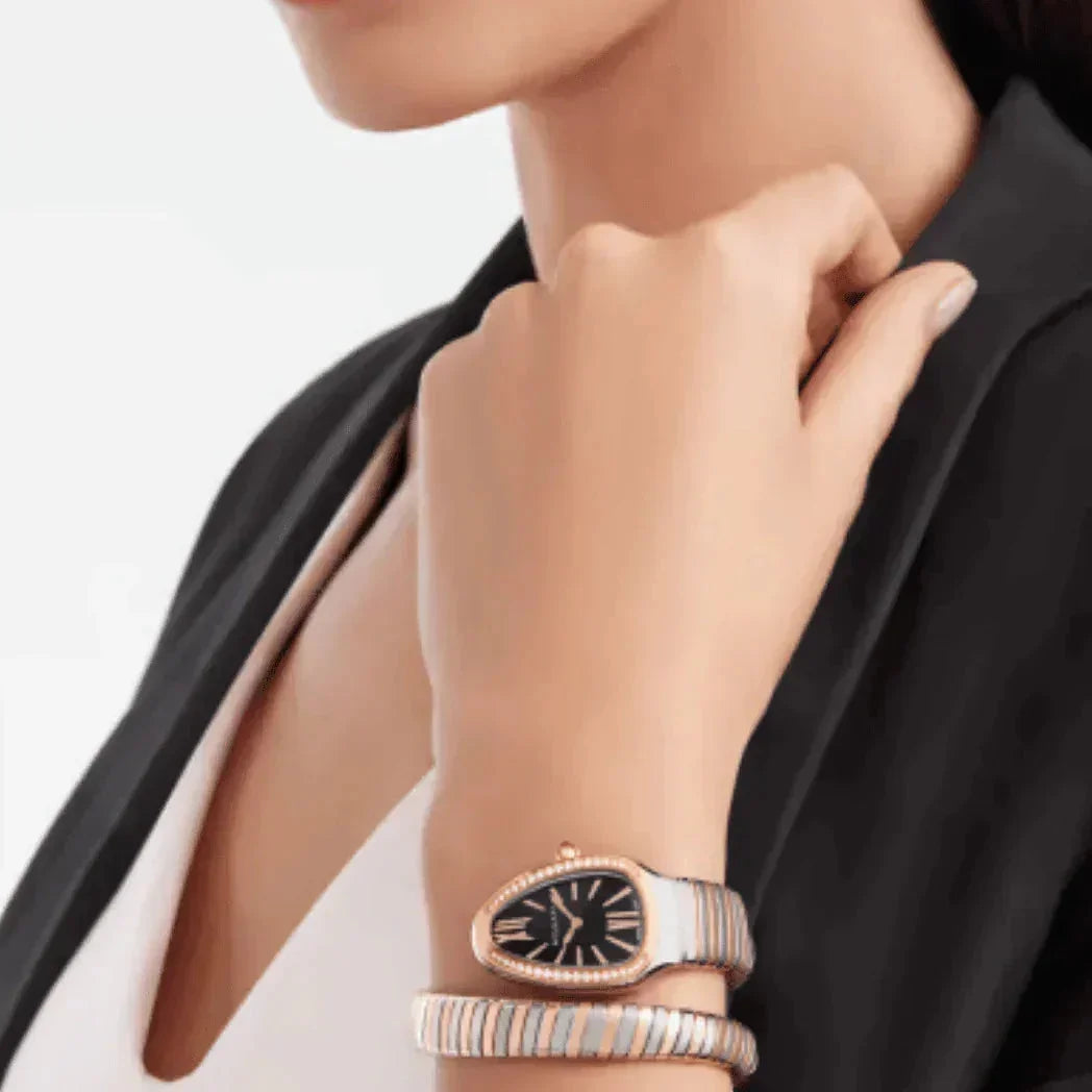 Woman wearing luxury snake-shaped gold and silver bracelet watch, black dial, business attire
