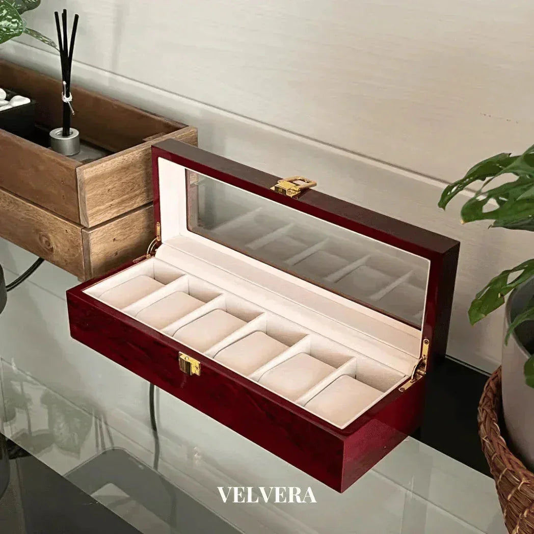 Luxury wooden watch box with glass lid, velvet interior, and gold clasp on a glass table