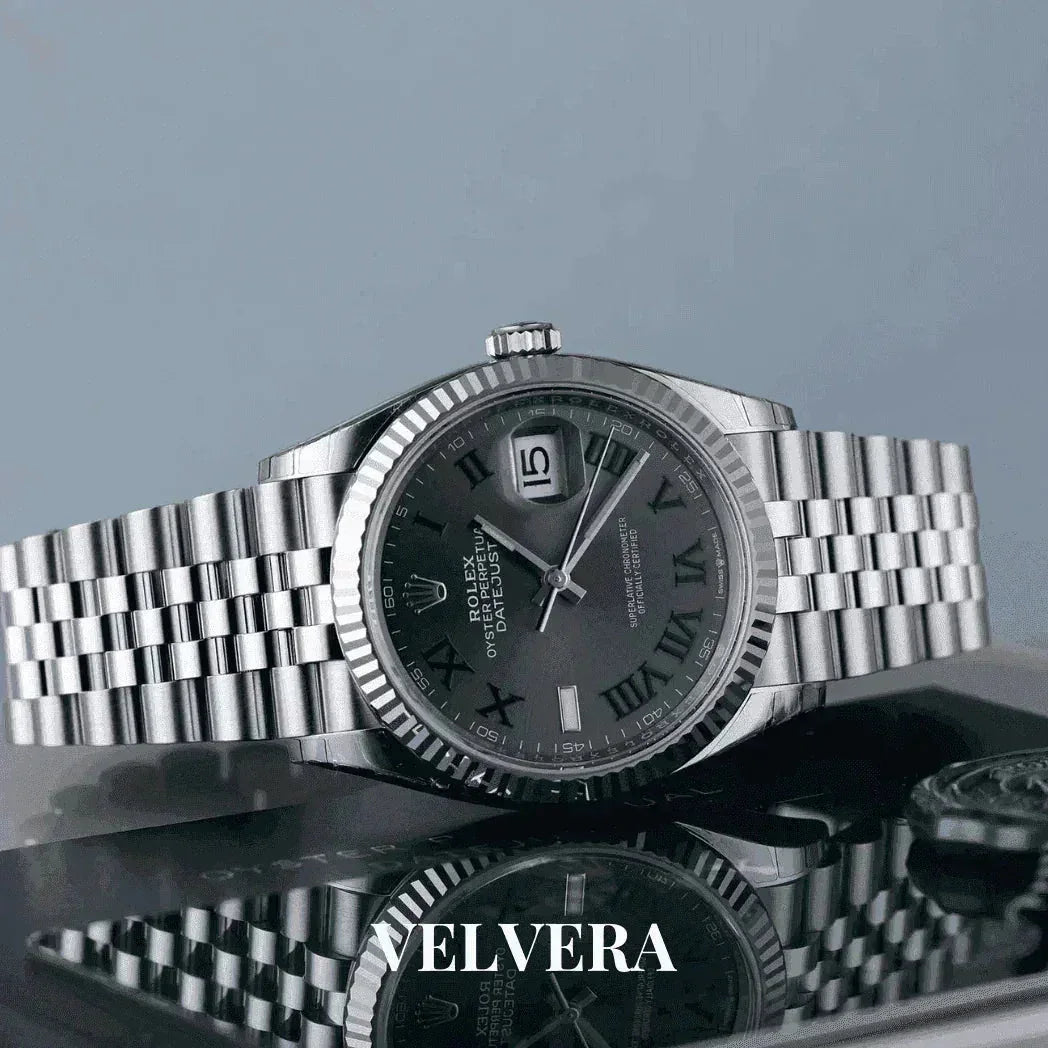 Silver Rolex Datejust watch with Roman numerals on a metal bracelet, displayed by Velvera