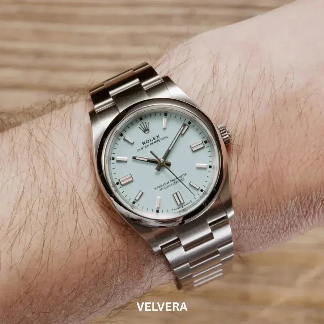 Stainless steel Rolex Oyster Perpetual with light blue dial on a wrist, wood background.