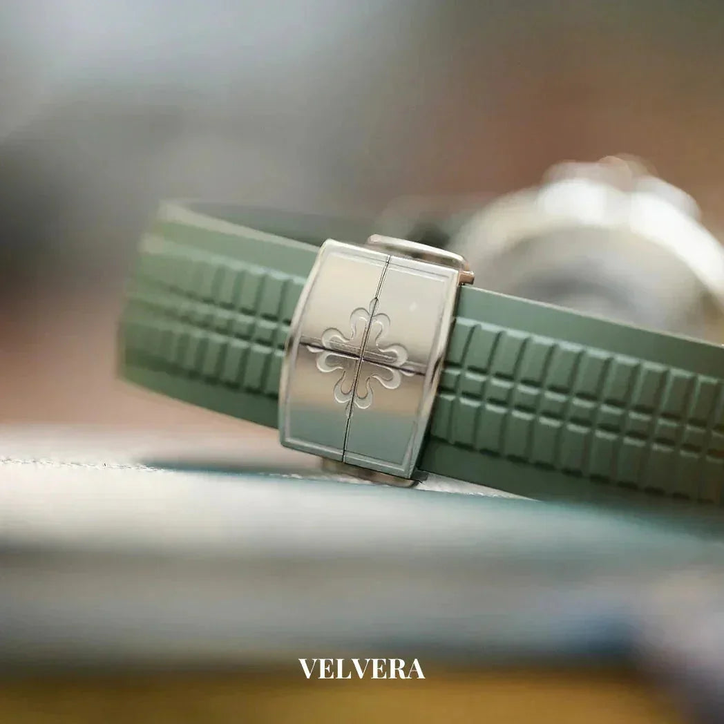 Close-up of green rubber watch strap with silver clasp and embossed logo, Velvera branding