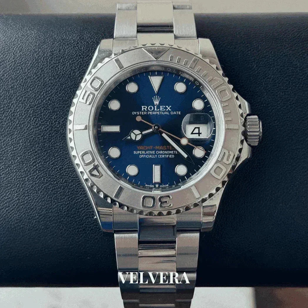 Rolex Yacht-Master stainless steel watch with blue dial and date, displayed on a black cushion.