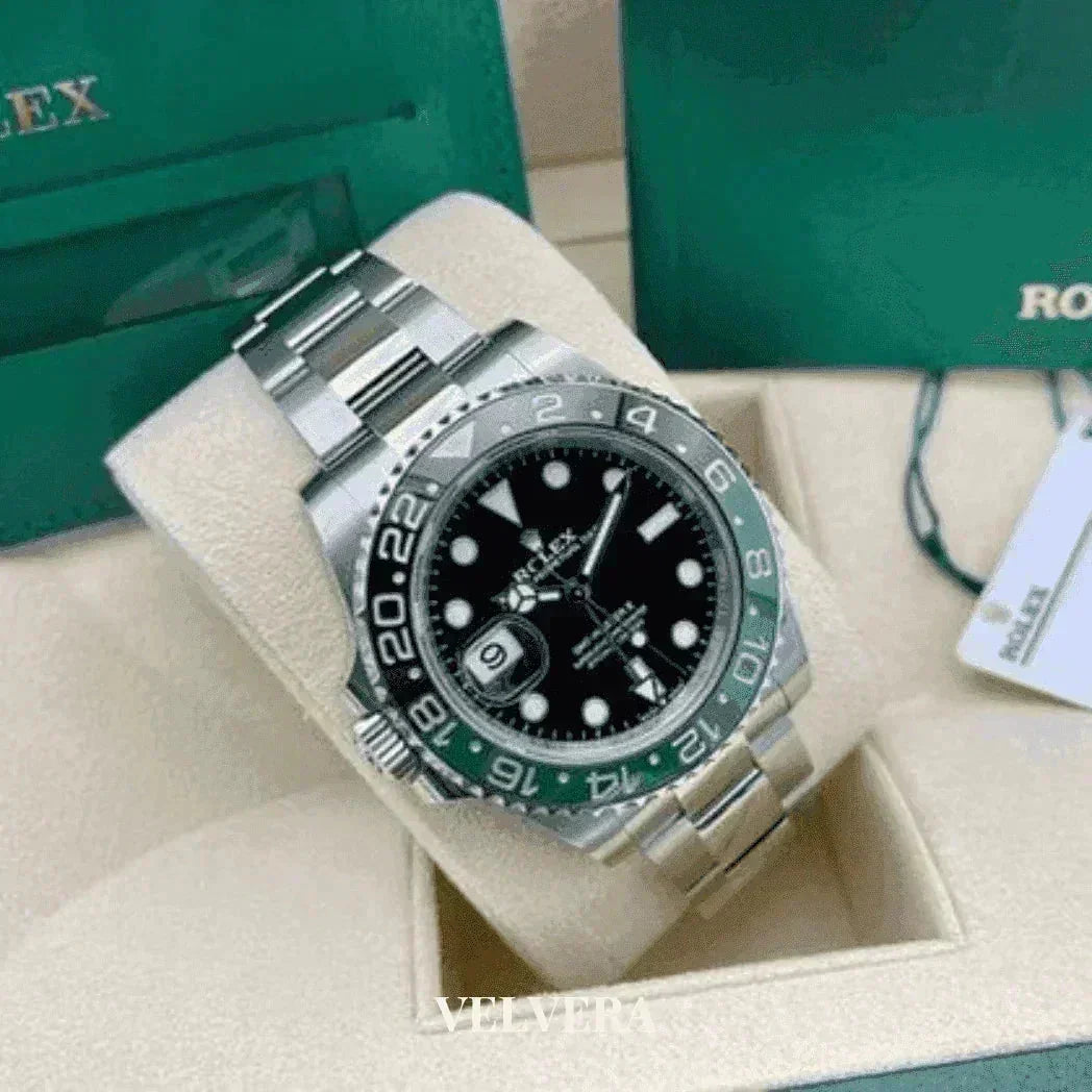 Stainless steel Rolex watch with black dial, green and black bezel, displayed in box.