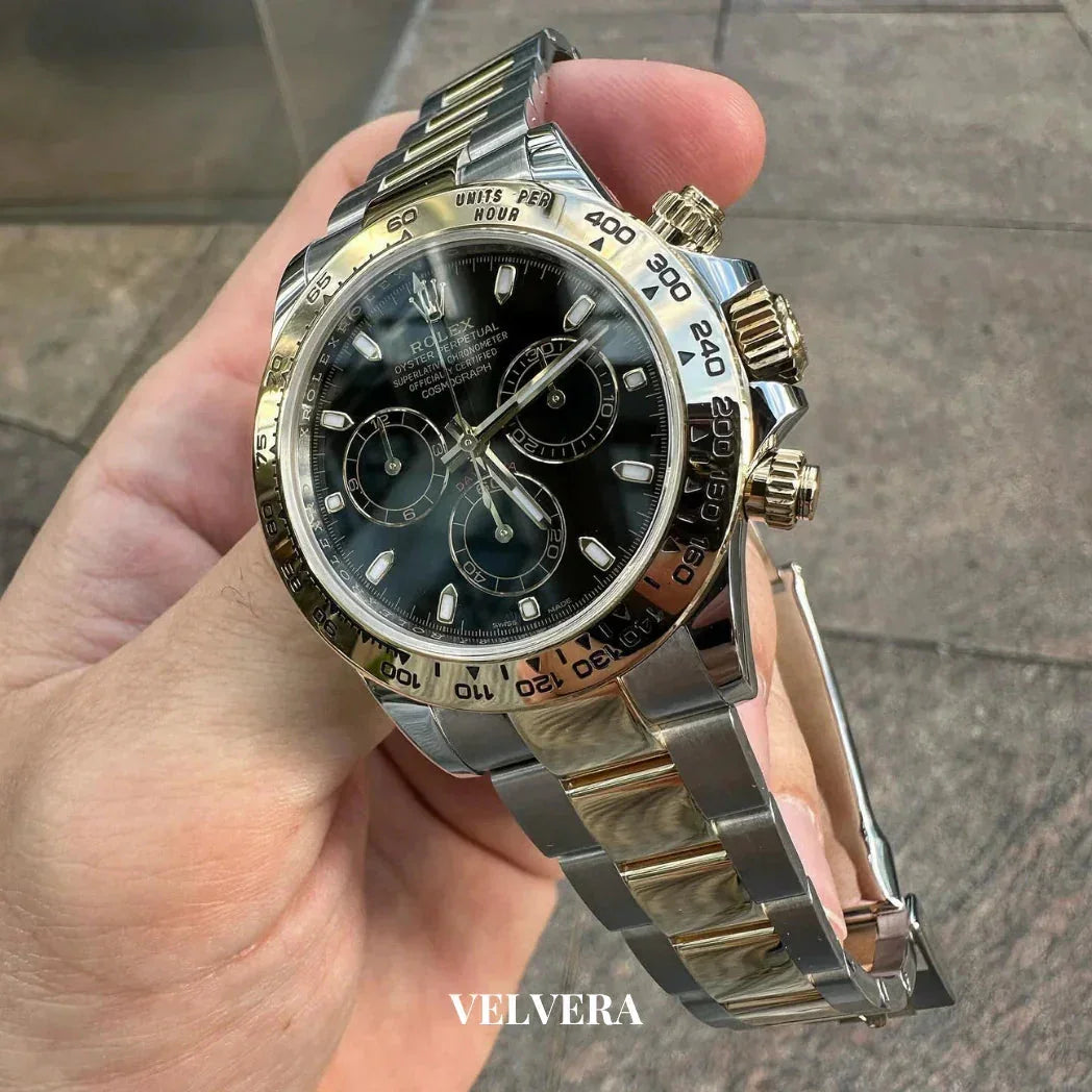 Luxury two-tone Rolex Daytona watch with black dial and gold accents, held outdoors