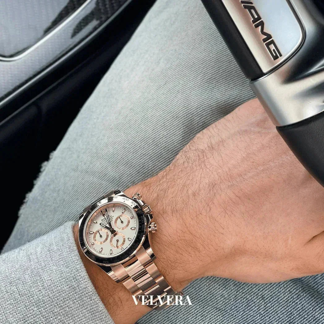 Luxury silver chronograph watch on wrist, hand on AMG steering wheel, VELVERA branding