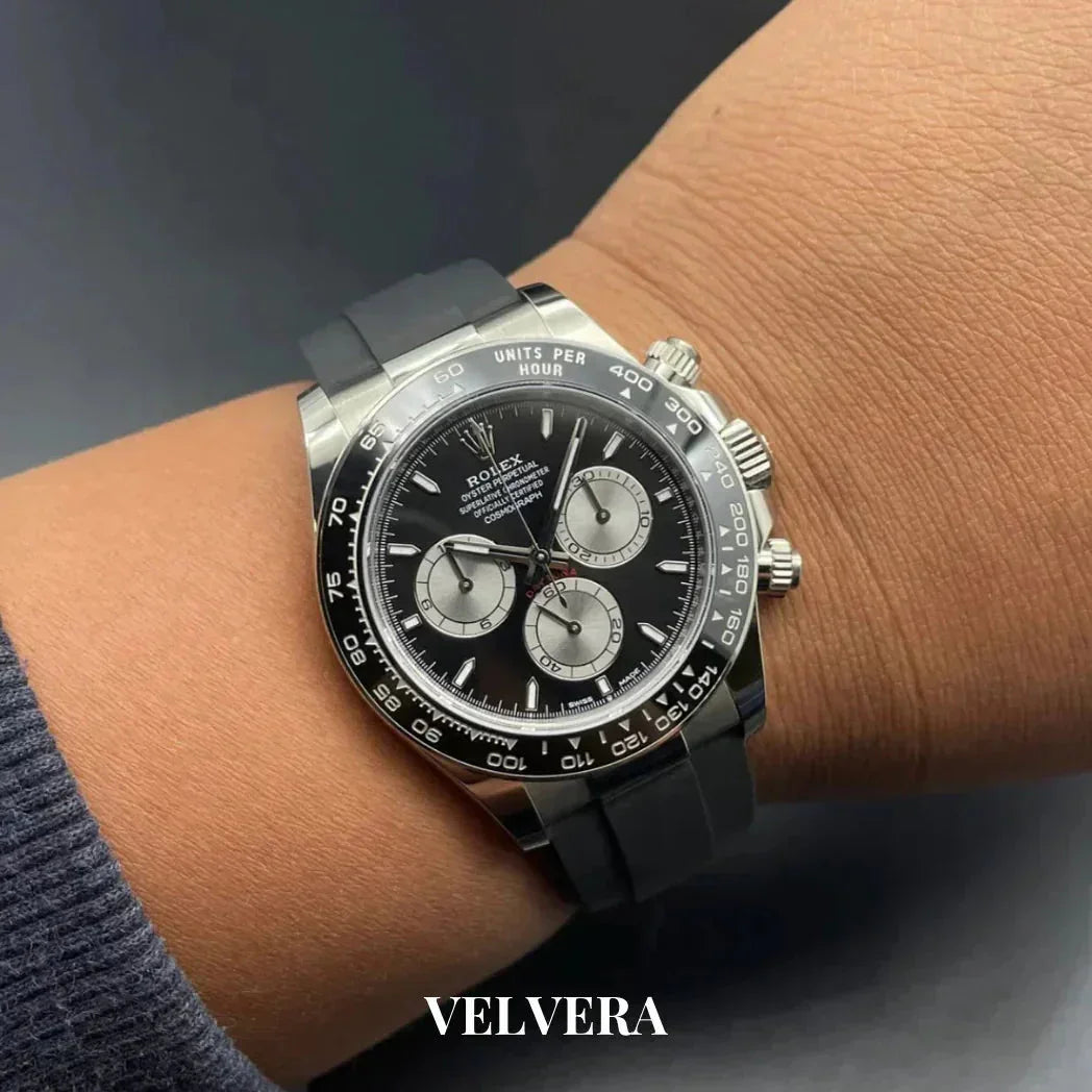 Black Rolex Daytona chronograph watch with rubber strap on wrist, Velvera branding visible