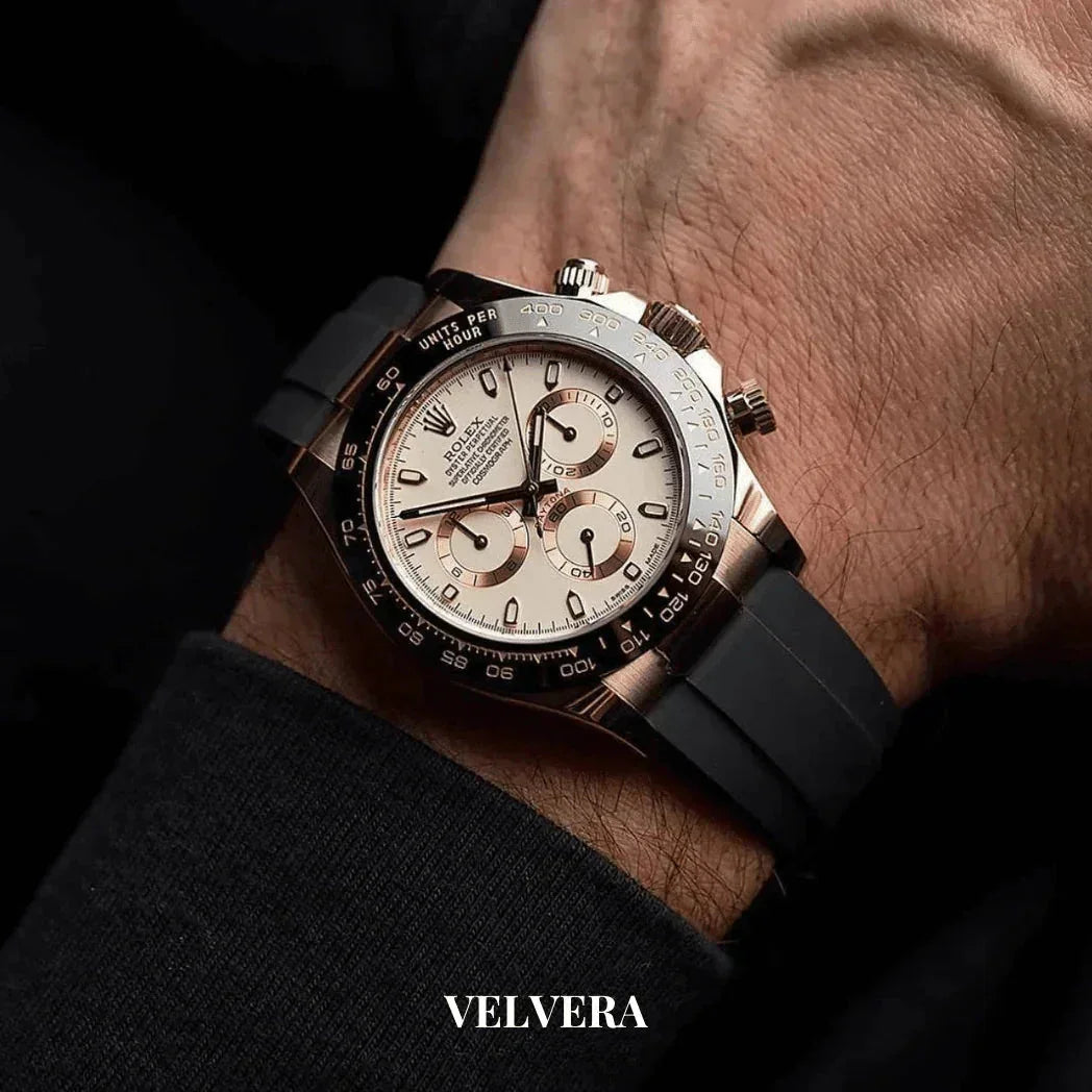 Luxury Rolex chronograph watch with black rubber strap and silver dial on wrist, Velvera