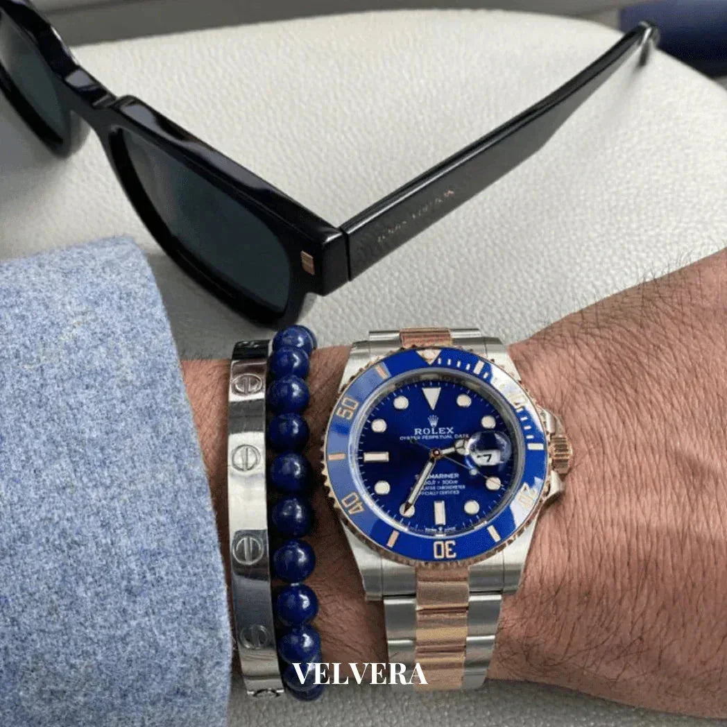 Man wearing a Rolex Submariner blue dial watch, silver bracelet, blue beaded bracelet, and sunglasses