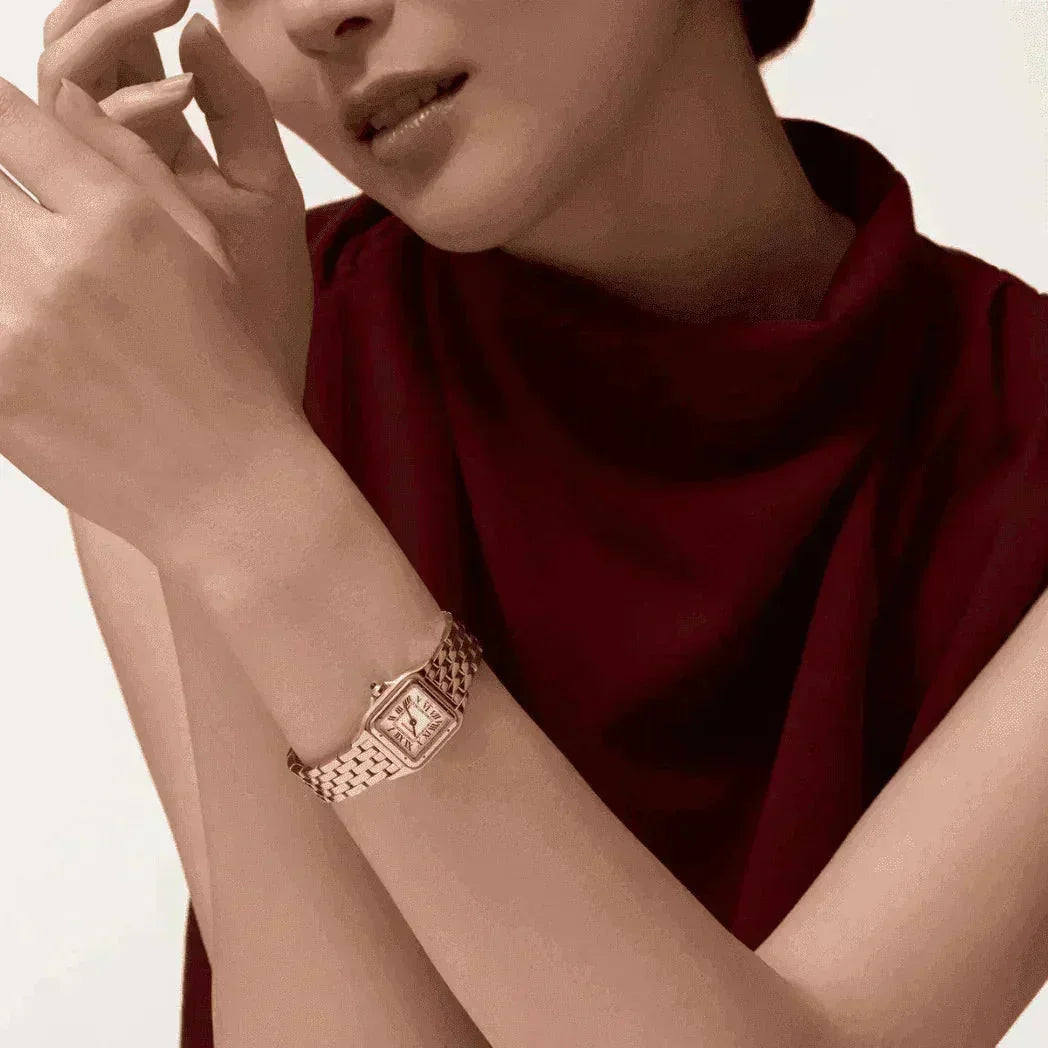 Woman wearing rose gold Panthere watch with square face and woven band, burgundy dress