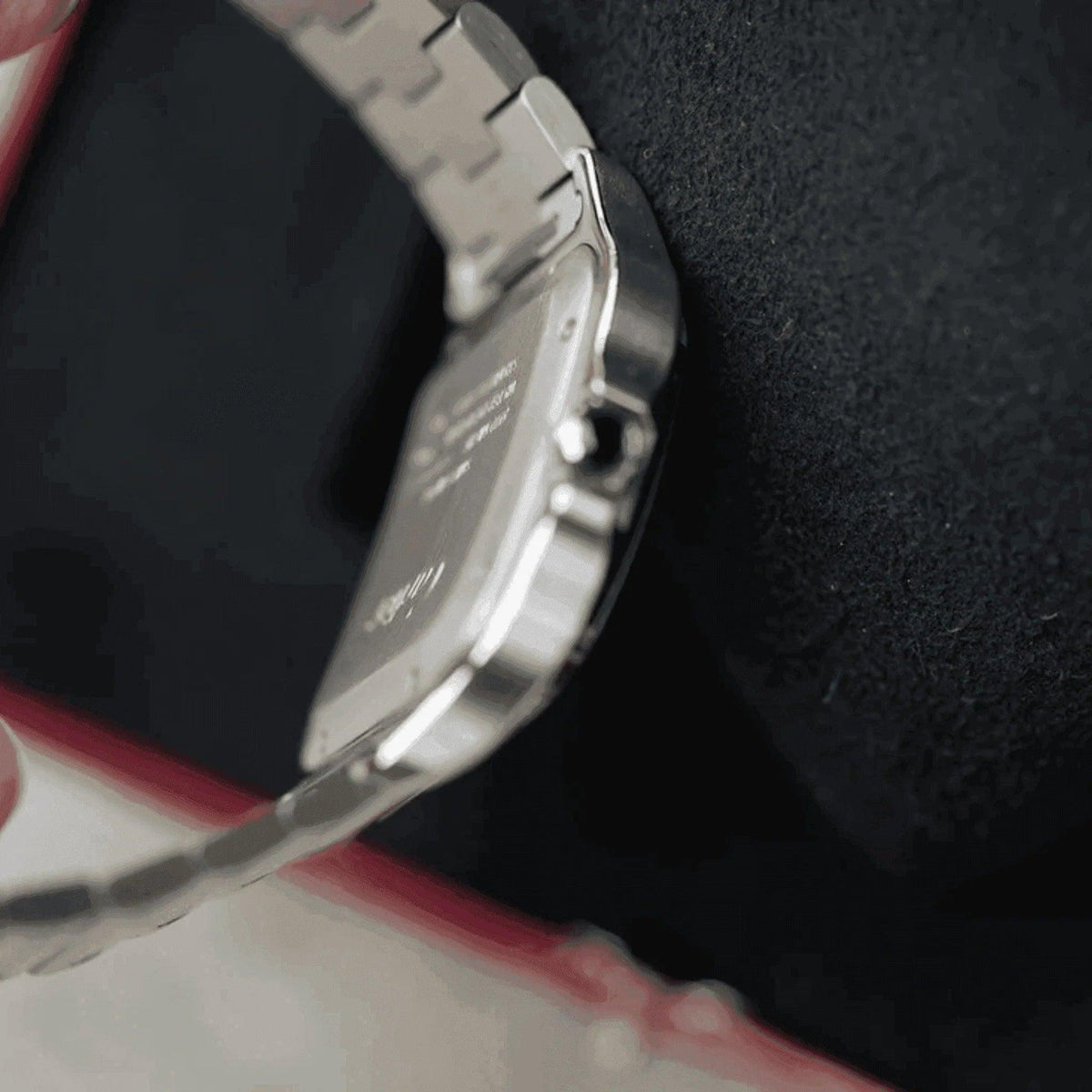Close-up of a silver men's Santos watch with metal bracelet on black cushion