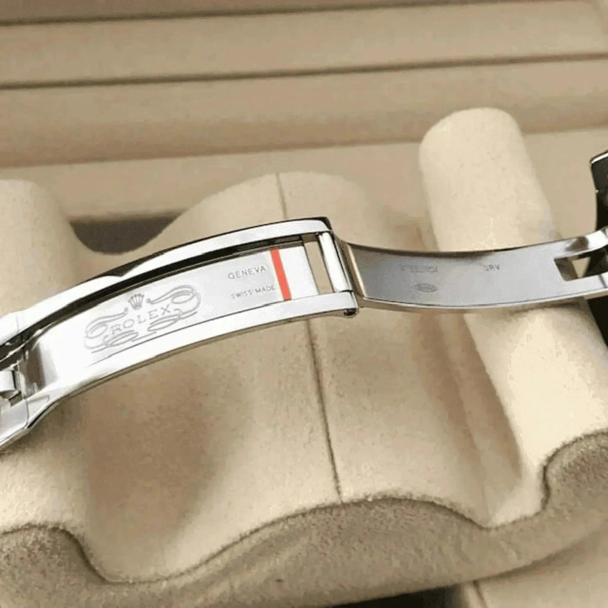 Men's classic stainless steel watch clasp on beige display, engraved for Geneva Swiss made
