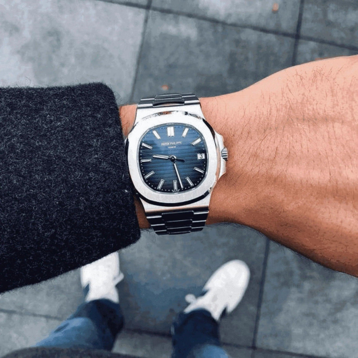 Man wearing a Patek Philippe Nautilus watch with blue dial and steel bracelet outdoors