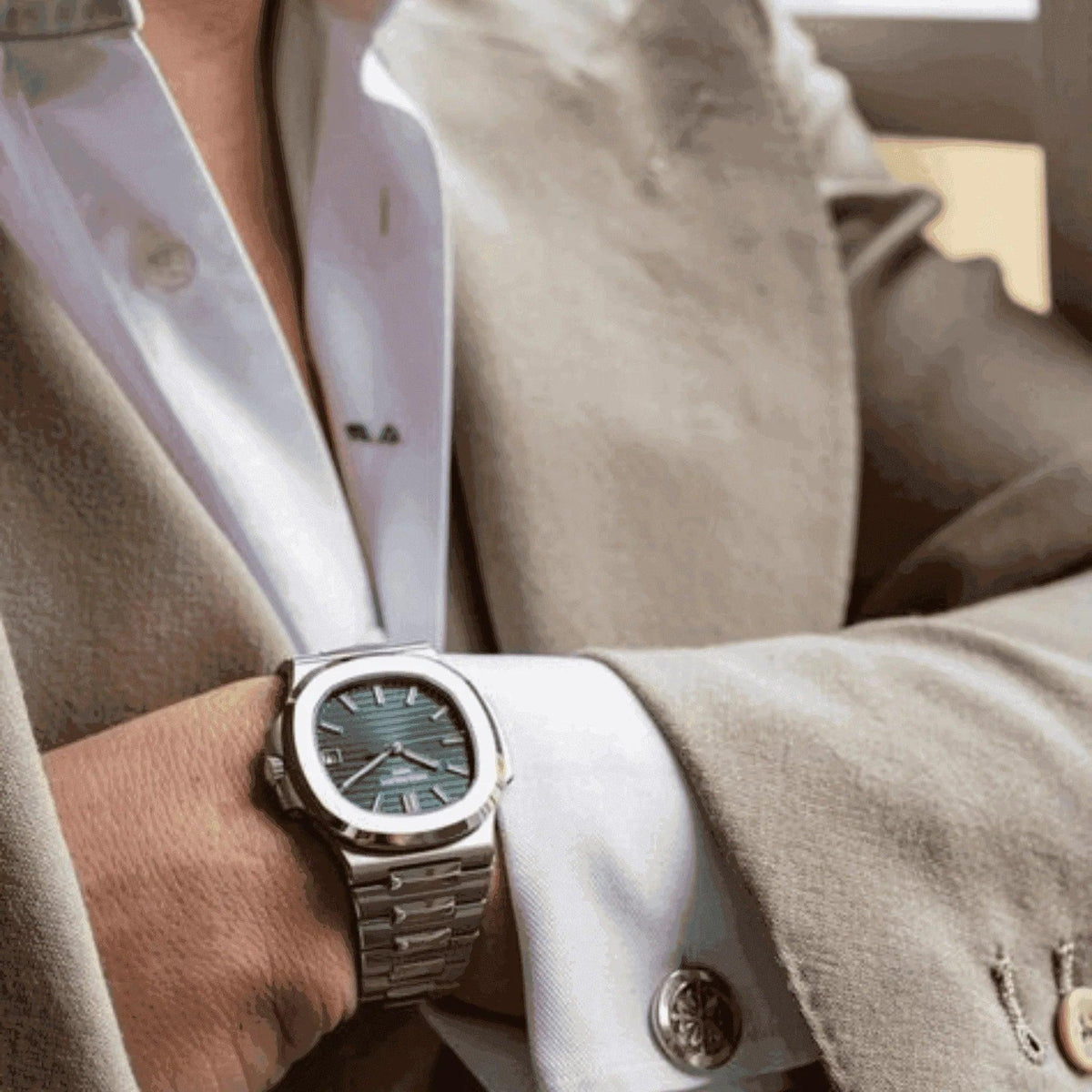 Luxury men's Patek Nautilus 5711A olive green watch on wrist with beige suit sleeve