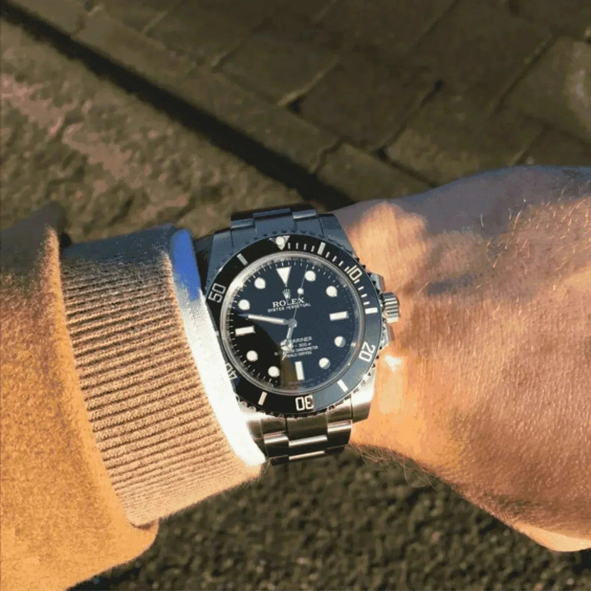 Rolex Submariner black dial men's watch with stainless steel bracelet on wrist outdoors