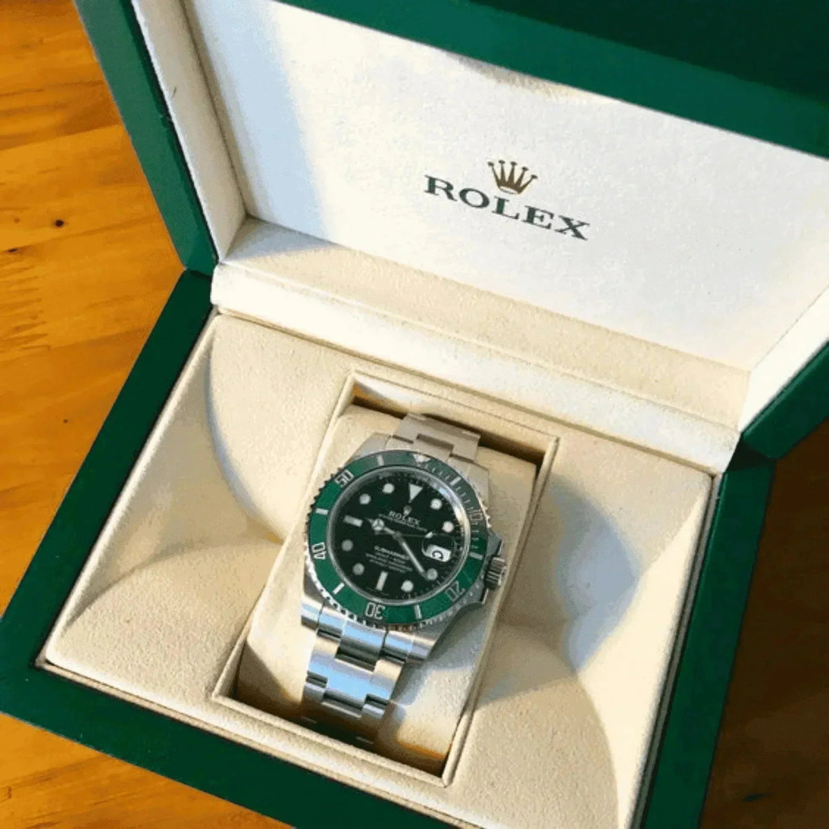 Green bezel Rolex Submariner Hulk 116610LV men's watch in branded box on wood surface