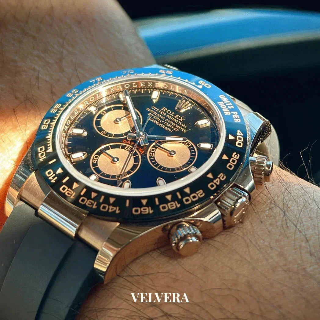 Rolex Daytona gold and blue chronograph watch with black rubber strap on wrist, VELVERA logo