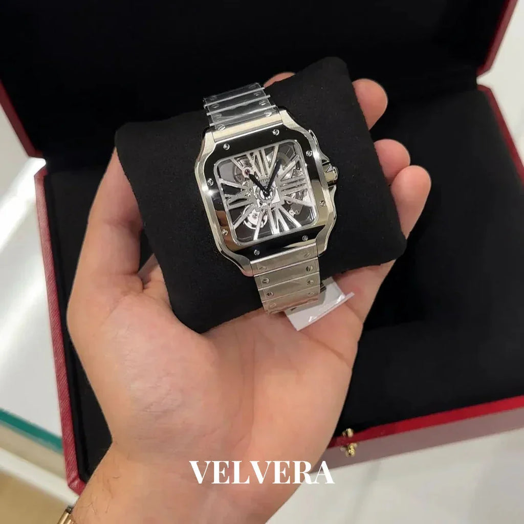 Luxury skeleton watch with silver metal band in hand, displayed in open red box, Velvera branding