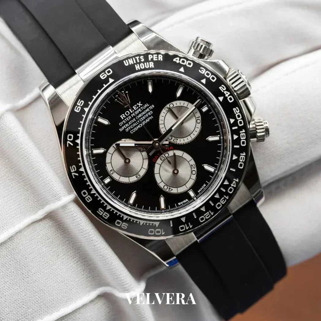Rolex black chronograph watch with rubber strap on white glove, luxury timepiece by Velvera