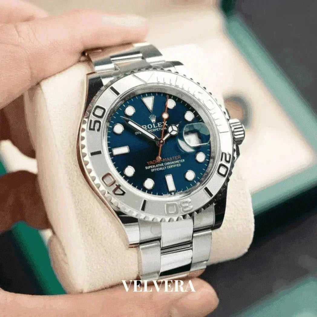 Silver Rolex Yacht-Master watch with blue dial held in hand, Velvera branding visible