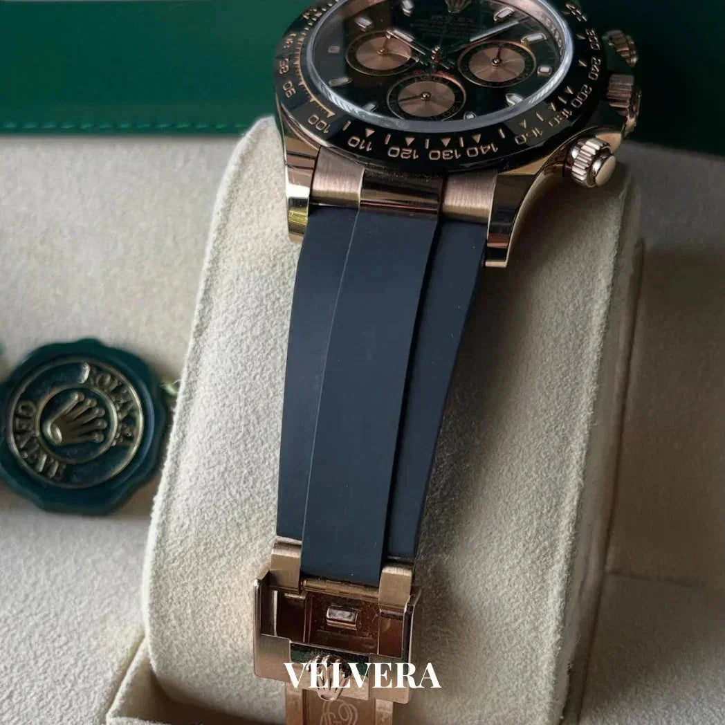 Luxury Rolex chronograph watch with black rubber strap on cream display, Velvera branding