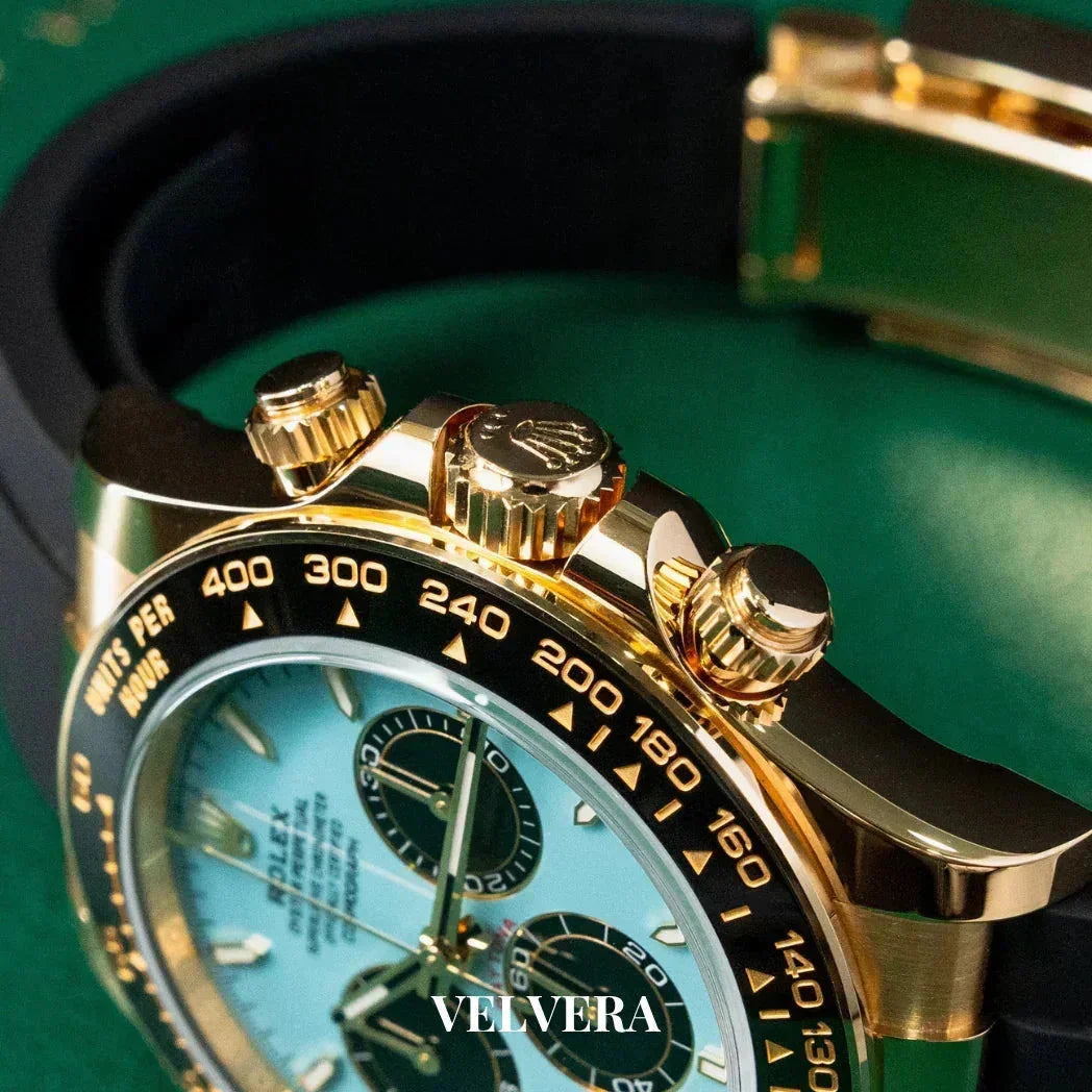 Luxury gold chronograph watch with black bezel and blue dial on green background