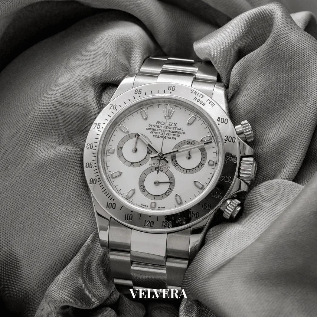Rolex Daytona stainless steel watch with white dial displayed on gray silk fabric, Velvera logo
