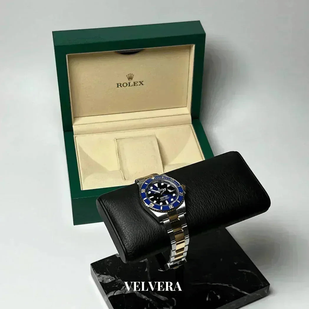 Rolex stainless steel watch with blue bezel on display, green Rolex box in background