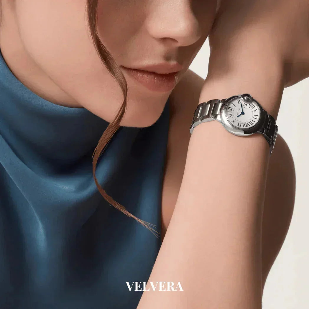 Woman in blue top wearing elegant silver wristwatch, Velvera branding visible