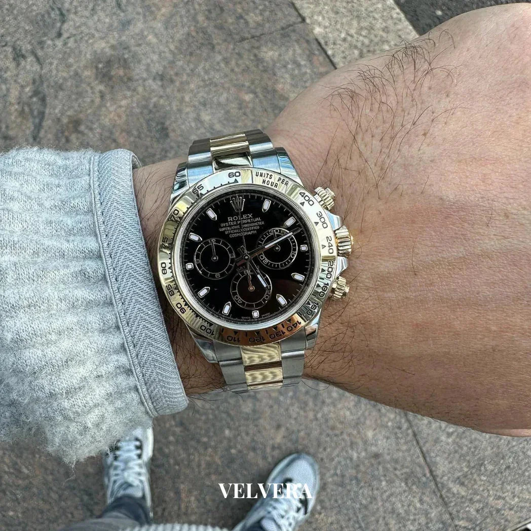 Luxury Rolex Daytona watch with black dial and gold accents on wrist outdoors, Velvera branding