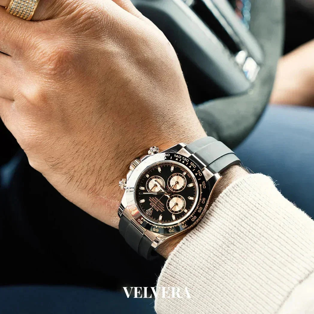 Luxury chronograph watch with black strap on man's wrist, hand on car steering wheel, Velvera logo