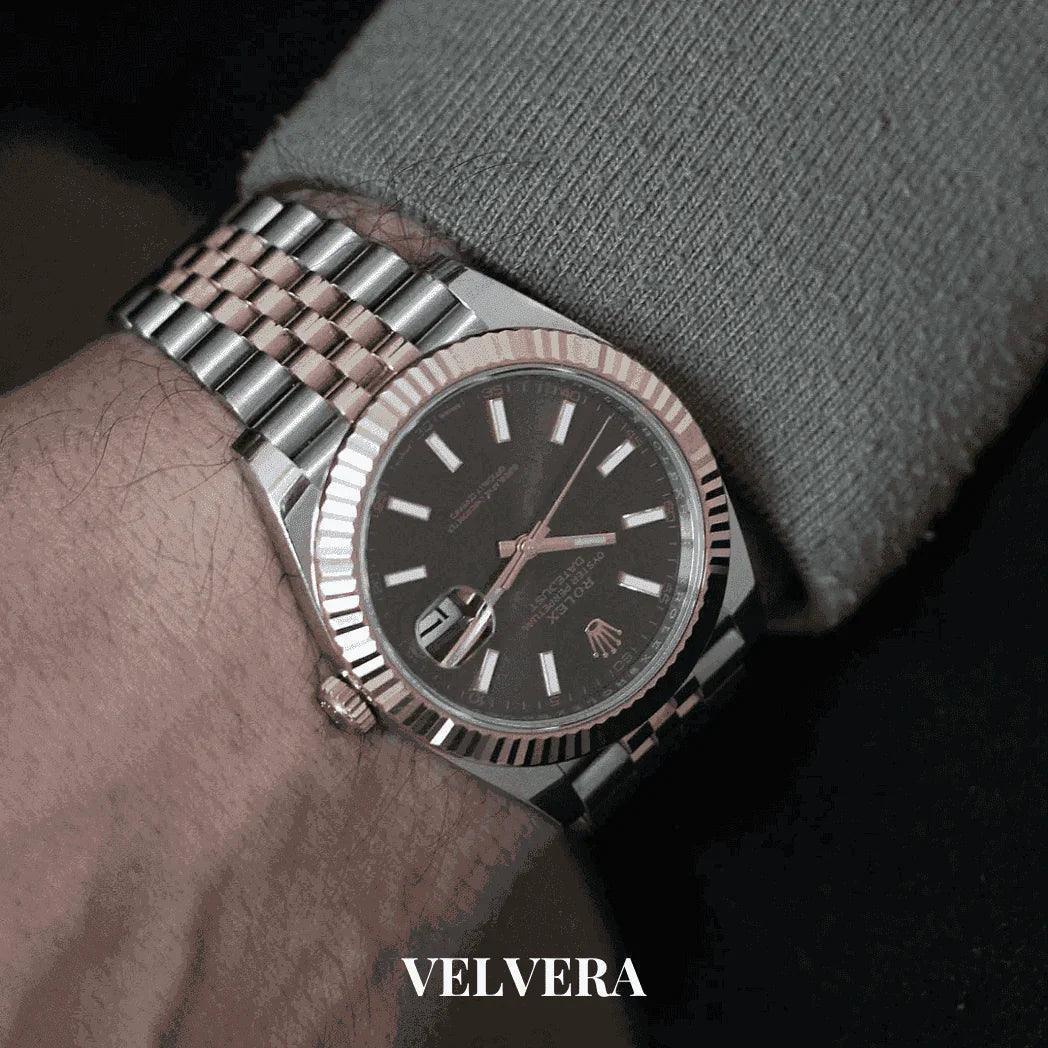 Luxury two-tone Rolex watch on wrist with black dial, metal band, and Velvera branding