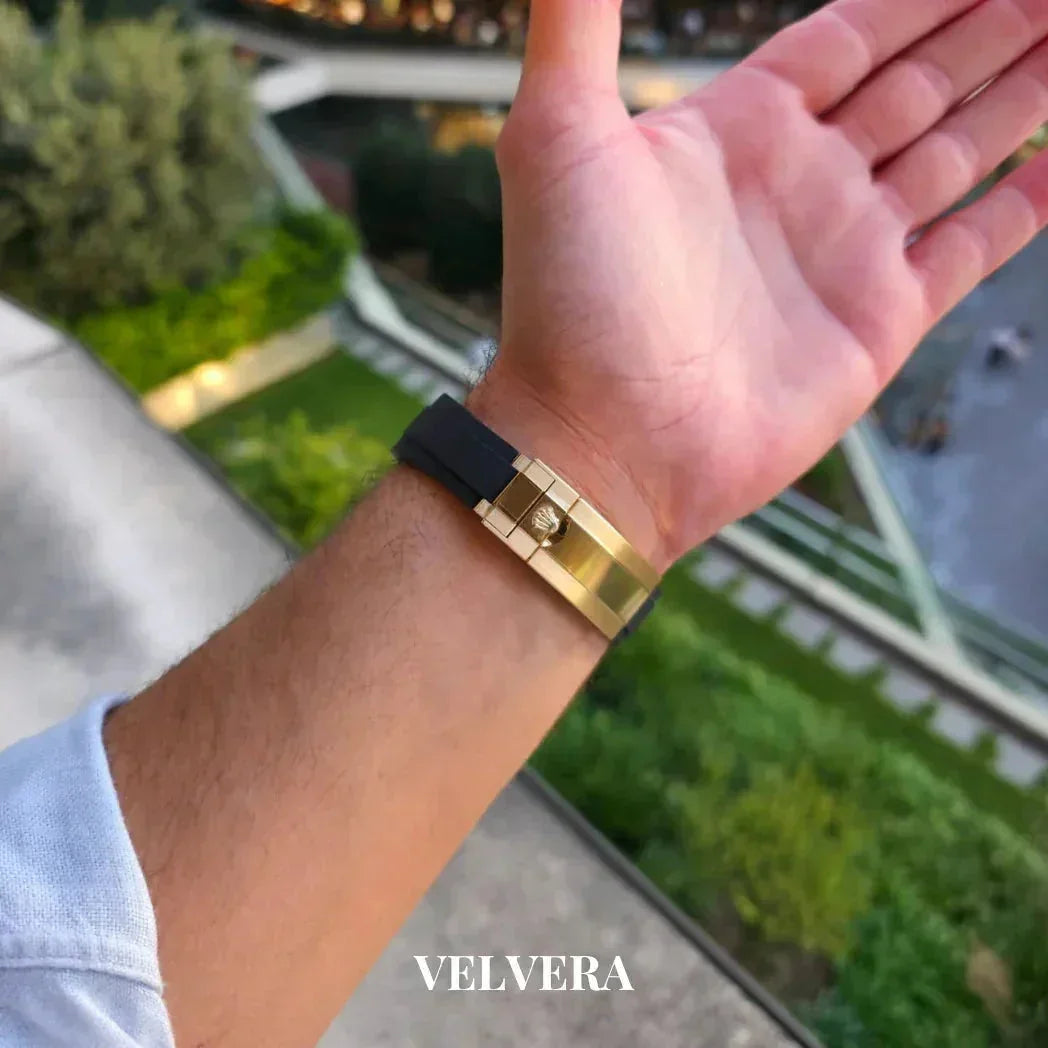 Man's wrist wearing gold and black bracelet outdoors, Velvera branding visible.