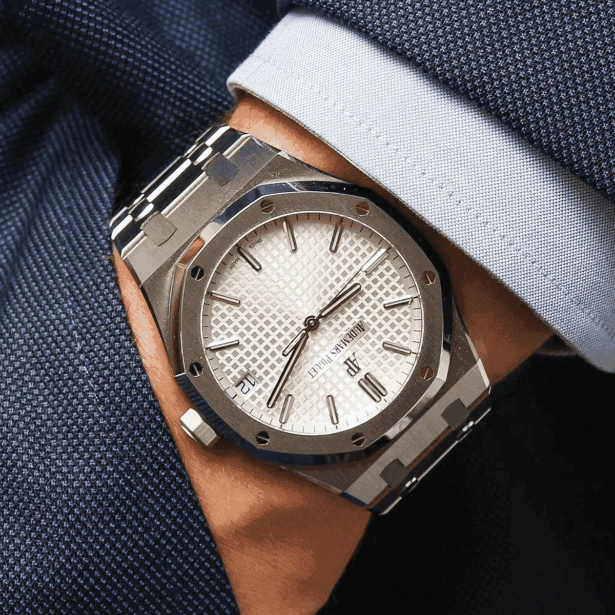 Luxury men's AP Royal Oak watch with white dial and steel bracelet on wrist in blue suit