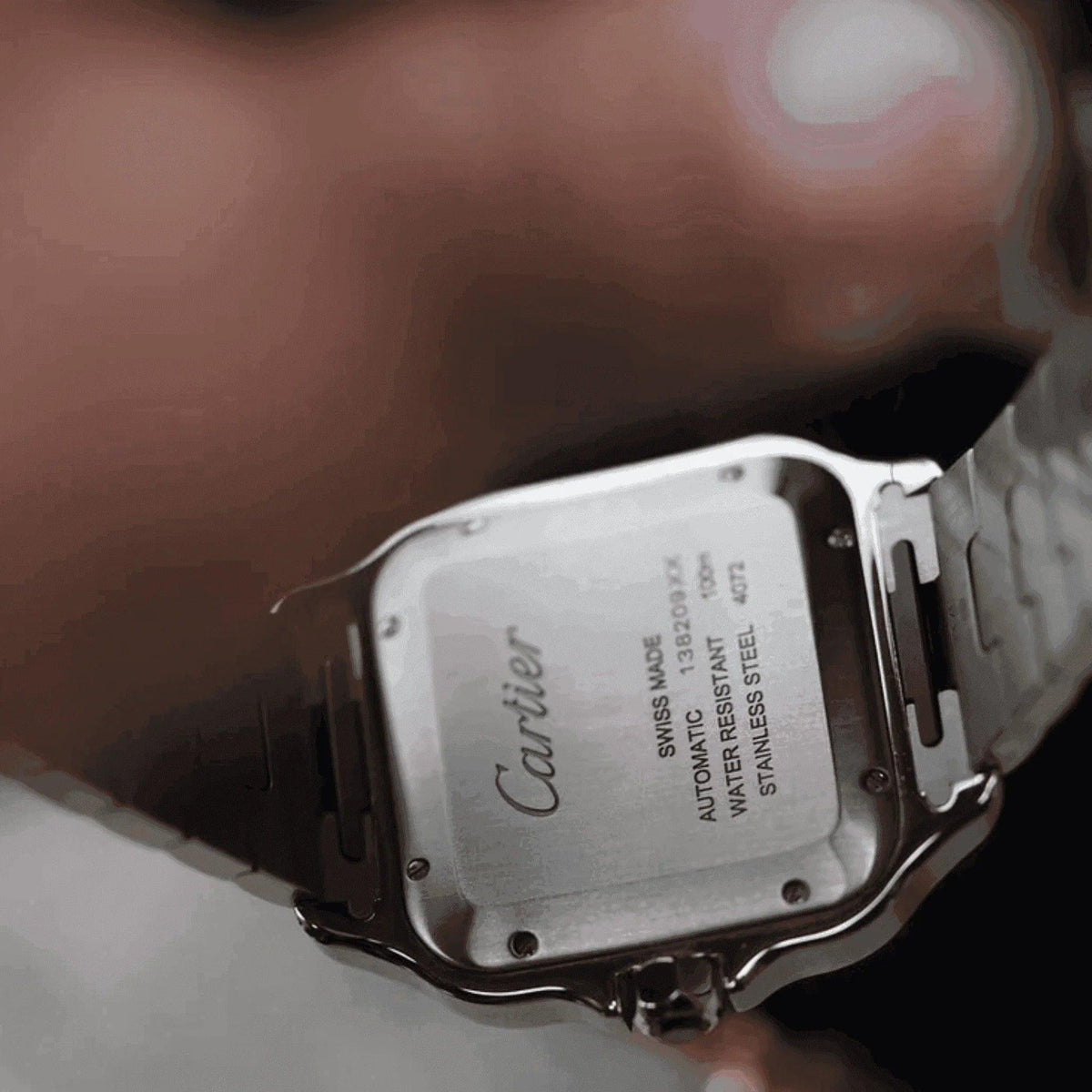 Close-up of Cartier Santos men's watch stainless steel caseback, engraved details visible