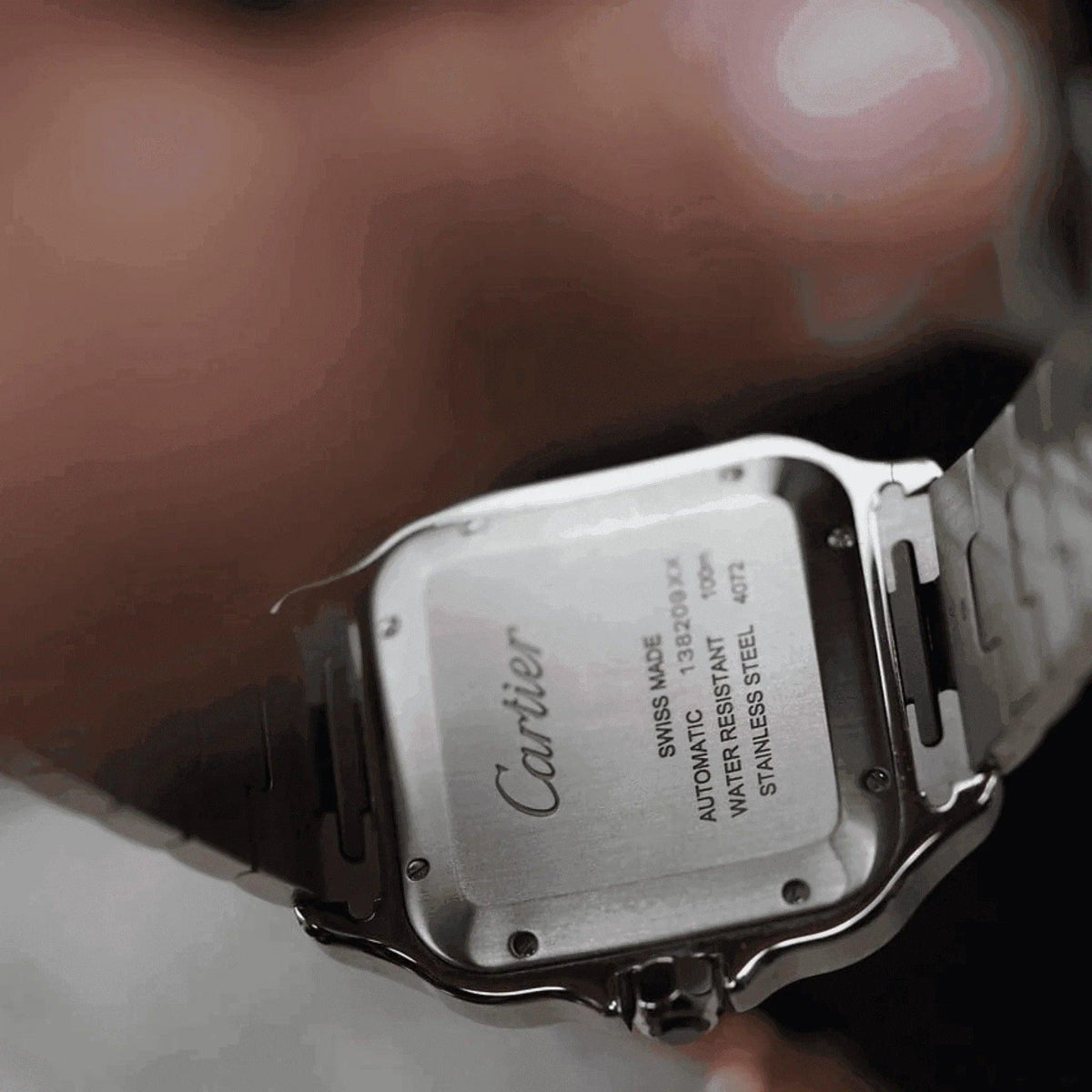 Close-up of Cartier Santos men's watch stainless steel case back, engraved details visible
