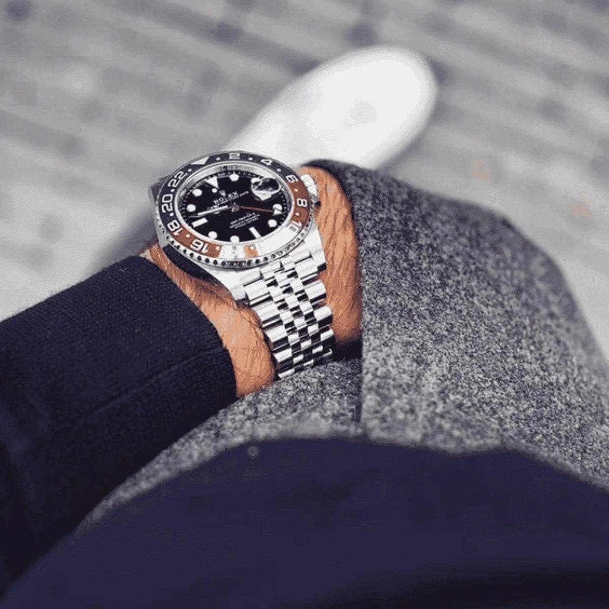 Men's luxury GMT Master II Pepsi watch with silver bracelet on wrist, stylish outfit
