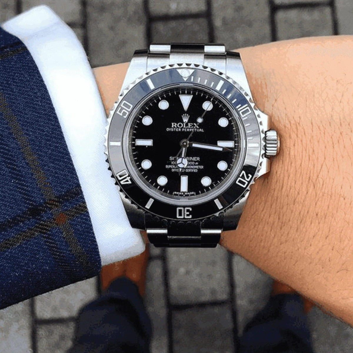 Rolex Submariner black dial men's watch worn with blue suit outdoors