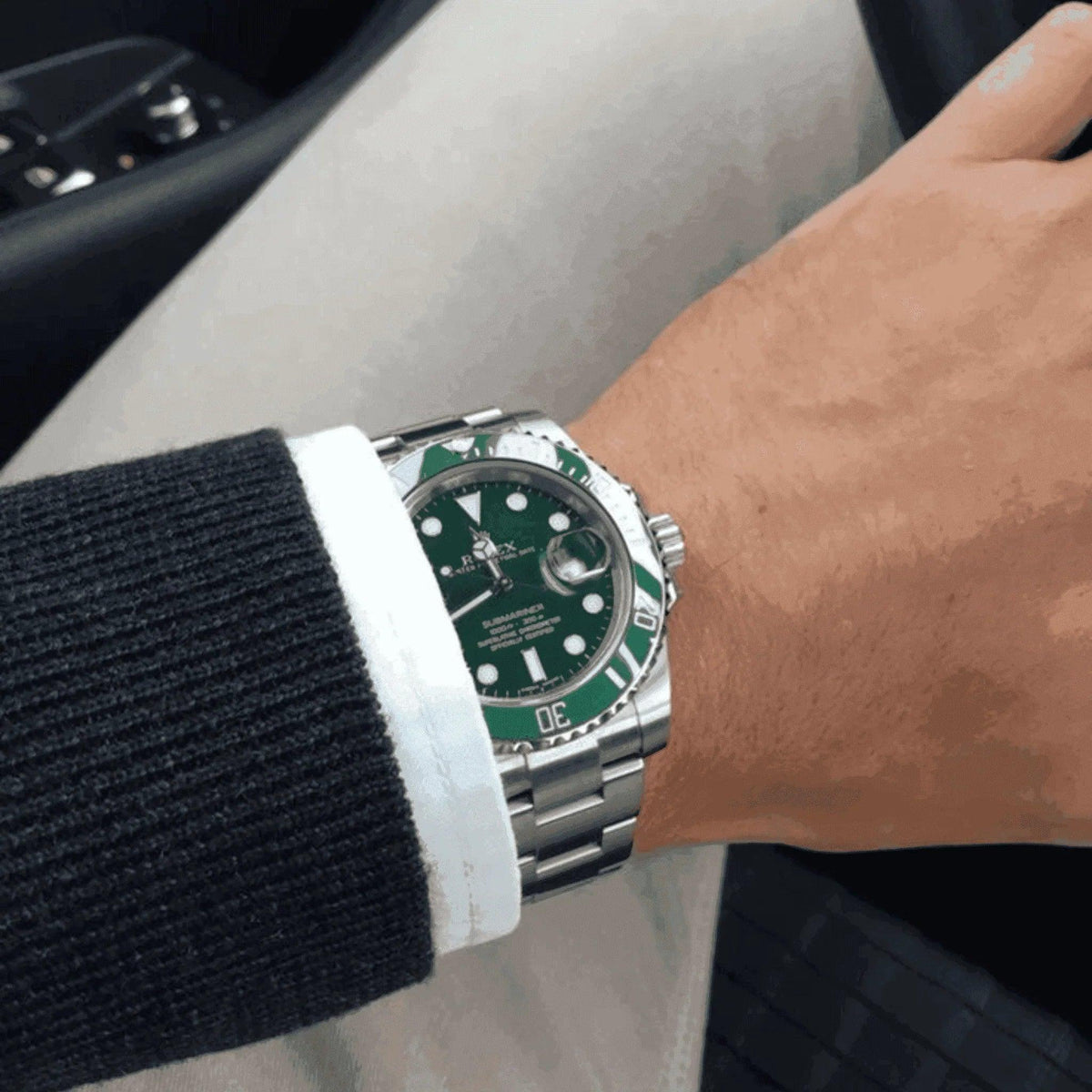 Man wearing green Rolex Submariner Hulk watch with stainless steel bracelet in car