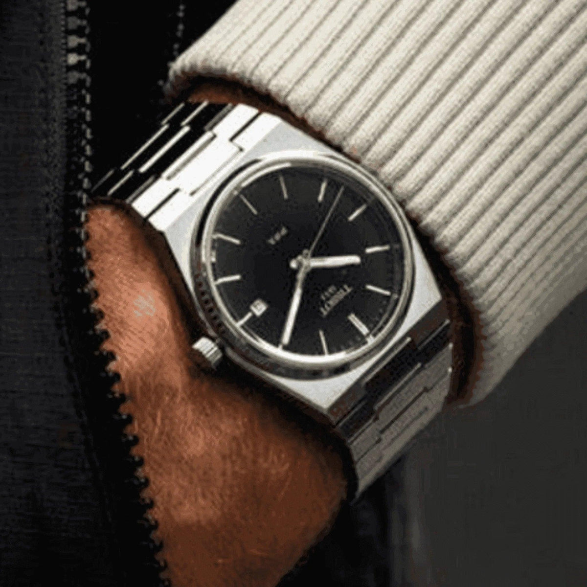 Men’s stainless steel watch with black dial and silver bracelet on wrist, close-up